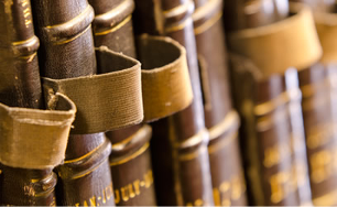 7 similar volumes from a single set of books on a shelf, bound in brown leather with gold text and each with a canvas loop attached to allow each book to be removed from the shelf.